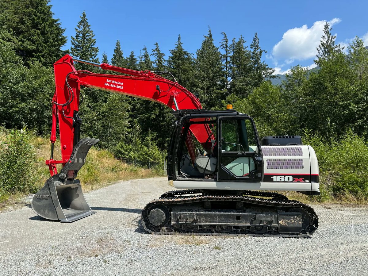 Bud Macleod excavator on a gravel access road surrounded by forest